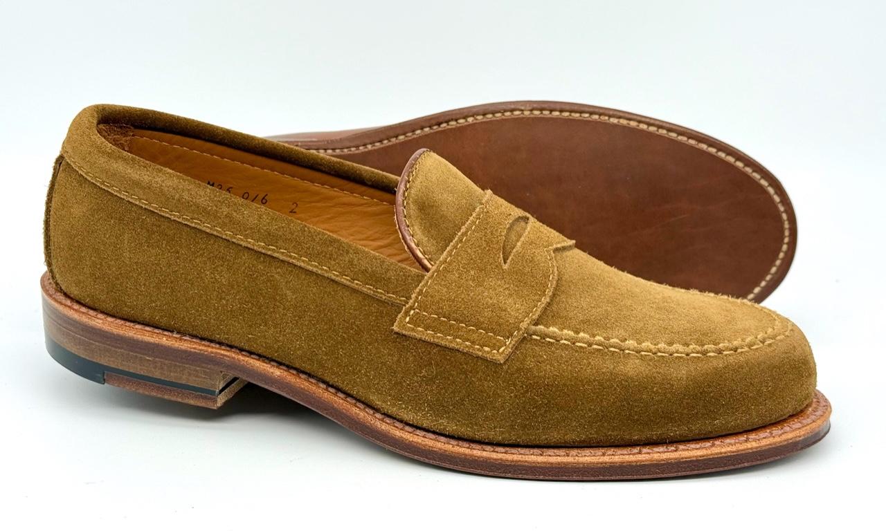 The Alden Madison 6173F Penny Loafer in snuff suede, crafted on the Van Last with a flex leather sole and low stacked heels, is shown on a white background—one shoe upright, the other revealing its sole.