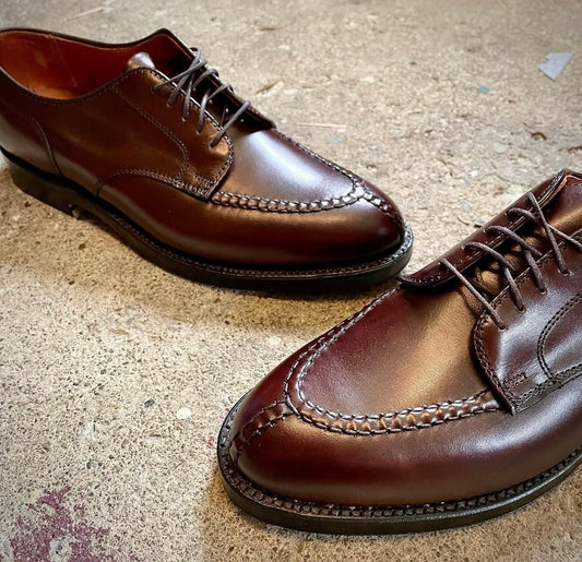 The Alden Madison 968 - Norwegian Split Toe Blucher in brown calfskin, featuring visible stitching and a double oak leather outsole, is displayed on a textured stone or concrete surface.