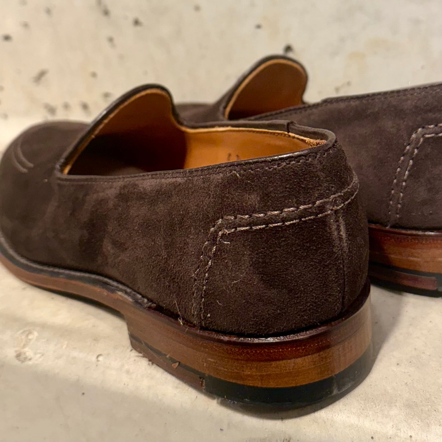 Close-up of the ALDEN SHOES D5105 - Vanderbilt in Dark Brown Suede with visible stitching and a Flex Leather Sole, set on a light surface against a speckled backdrop.