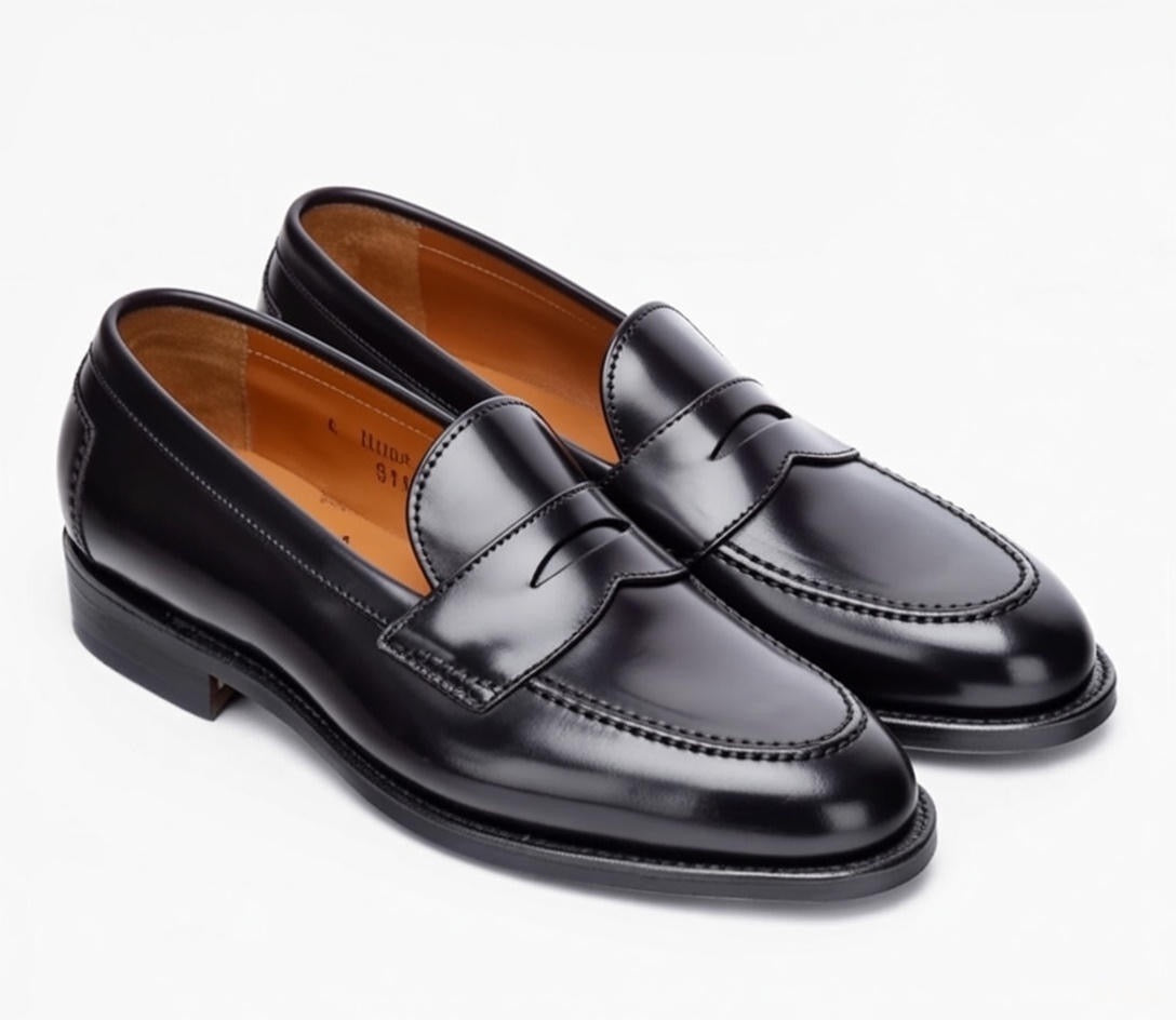 The Alden Madison 96949 Copley Penny Loafers in black Shell Cordovan feature classic stitching, rounded toes, tan interiors, and durable leather soles—shown side by side on a white background.