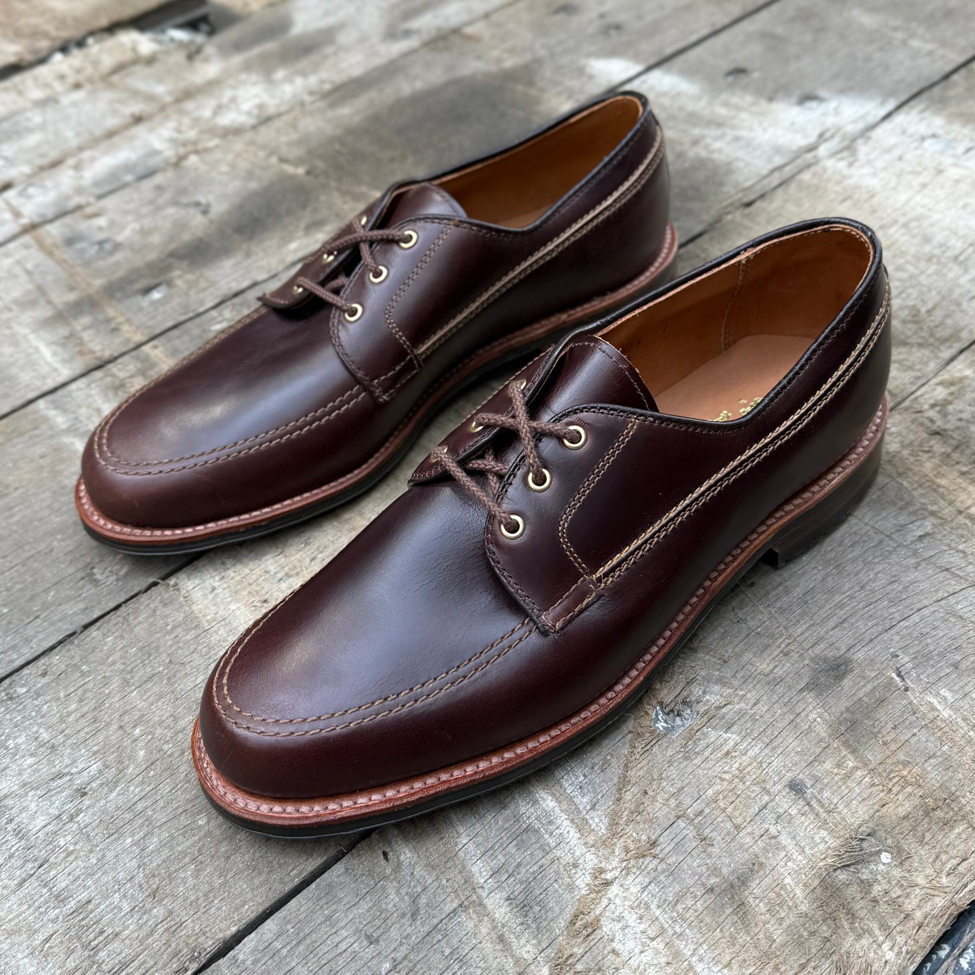 Alden Madison 734L - Ivy Blucher in Brown Chromexcel leather with tan stitching and a Leisure Rubber Sole, displayed on a rustic wooden surface.