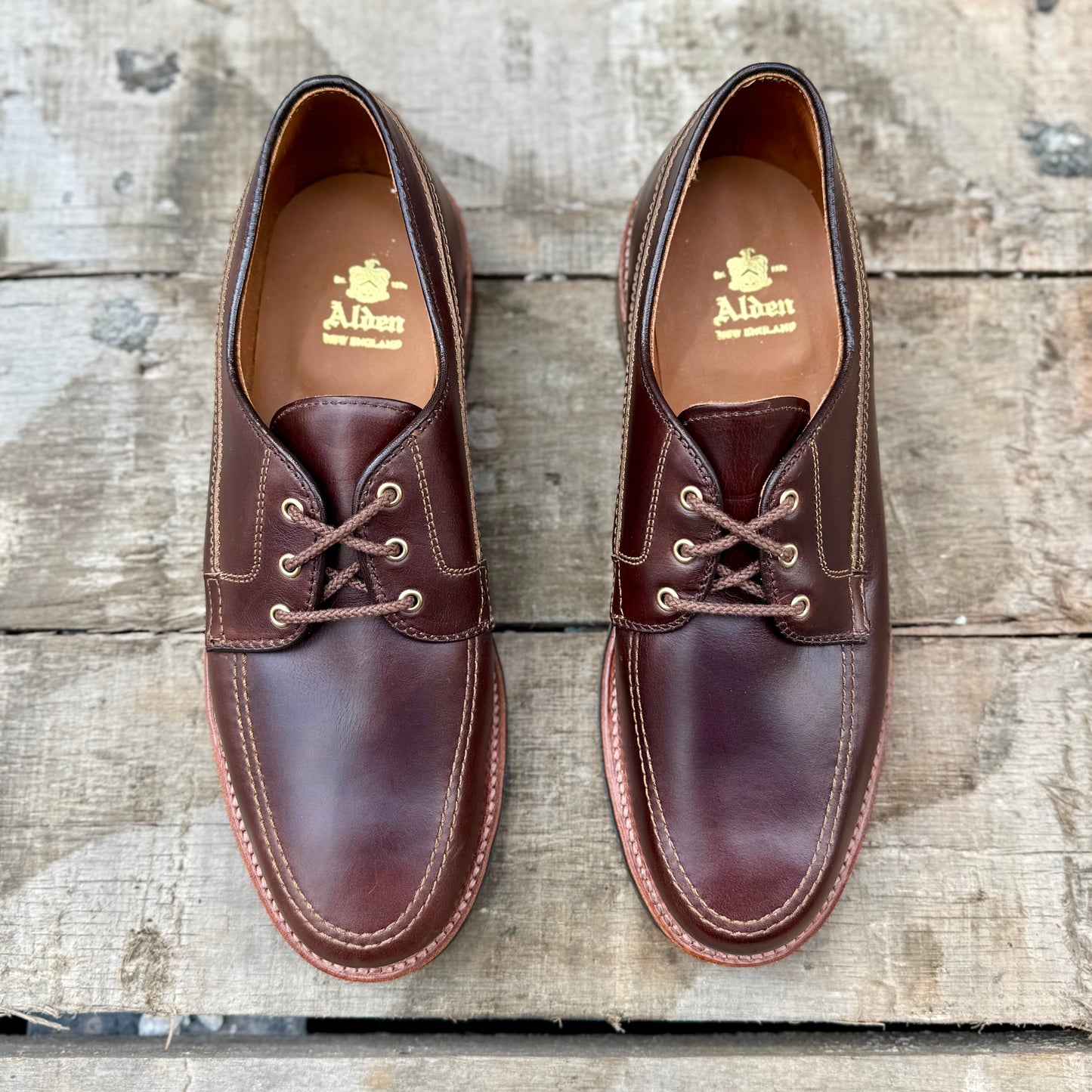 Alden Madison 734L - Ivy Blucher in Brown Chromexcel leather, featuring visible stitching, displayed side by side on a weathered wooden surface.