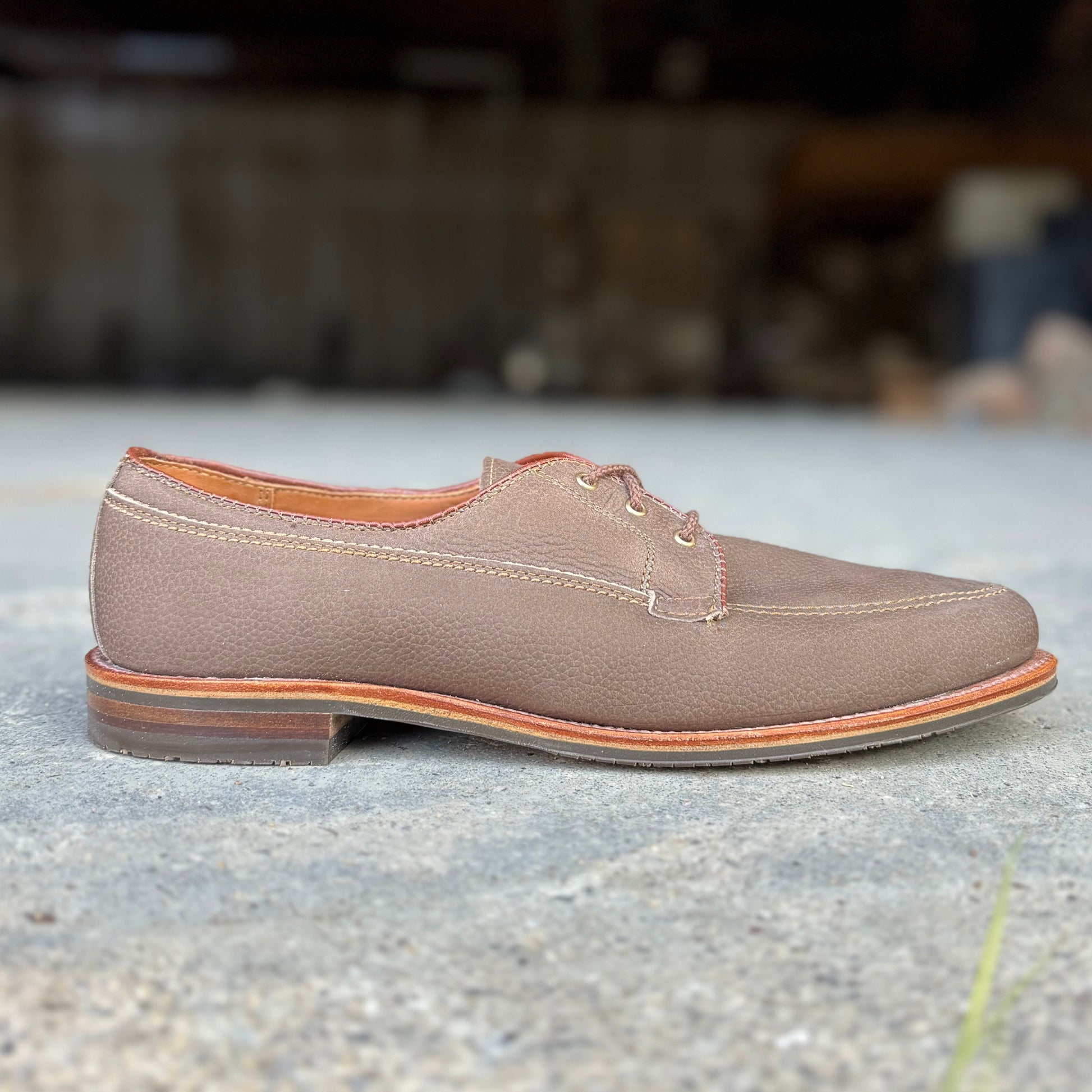 A single Alden Madison 7351 - Ivy Blucher in brown Clay Nubuck leather with tan stitching and a wooden sole is displayed on concrete, with a blurred background.