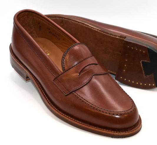 Alden Madison’s 9826 Penny Loafer in Walnut Michigan Calf features stitched detailing, a flex oiled leather sole, and is crafted on the Van Last—shown with one shoe upright and the other displaying its sole and heel.