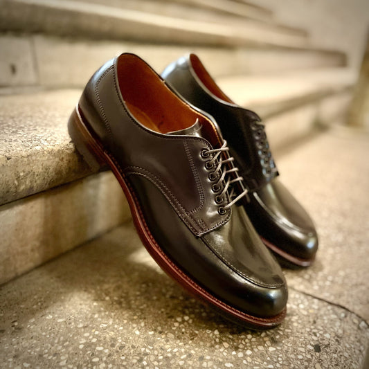 Alden Madisons D1629C - V Tip Split Toe Blucher in Color 8 Shell, featuring brown commando soles, rests on a stone staircase. The neatly laced shoes stand out against the blurred stone steps.