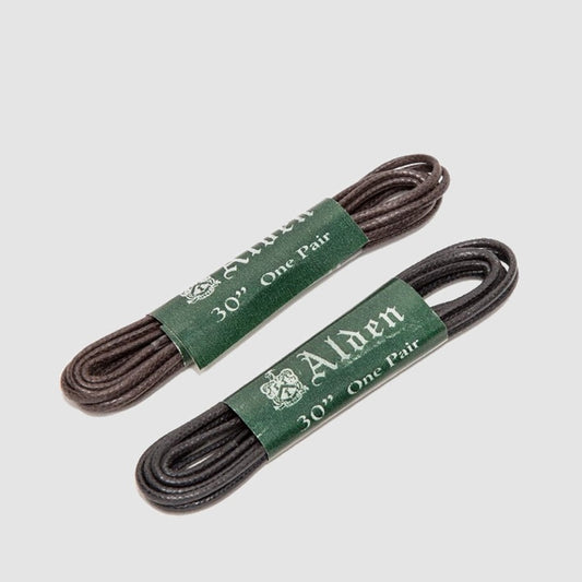 Two pairs of Alden Madison Shoe Laces, each 30 inches long, come coiled with green labels displaying the brand logo. One pair is dark brown and the other black. These round wax shoe laces are perfect for classic footwear, set against a light gray background.