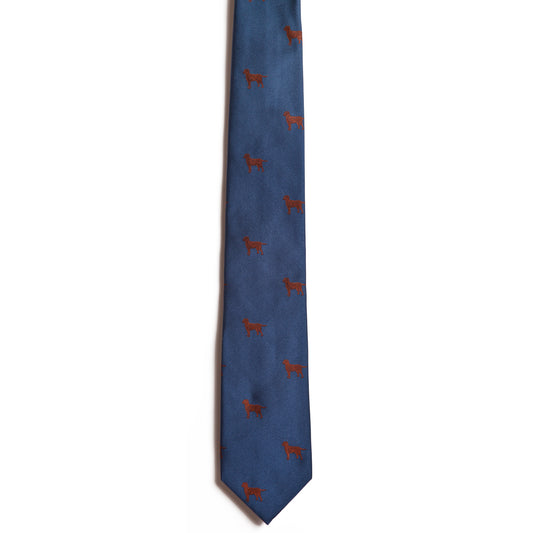 Explore the Chocolate Lab from Alden Madison, a blue necktie with small red embroidered dogs evenly spaced across the fabric. Crafted from 100% silk, it adds sophistication to a plain white background.